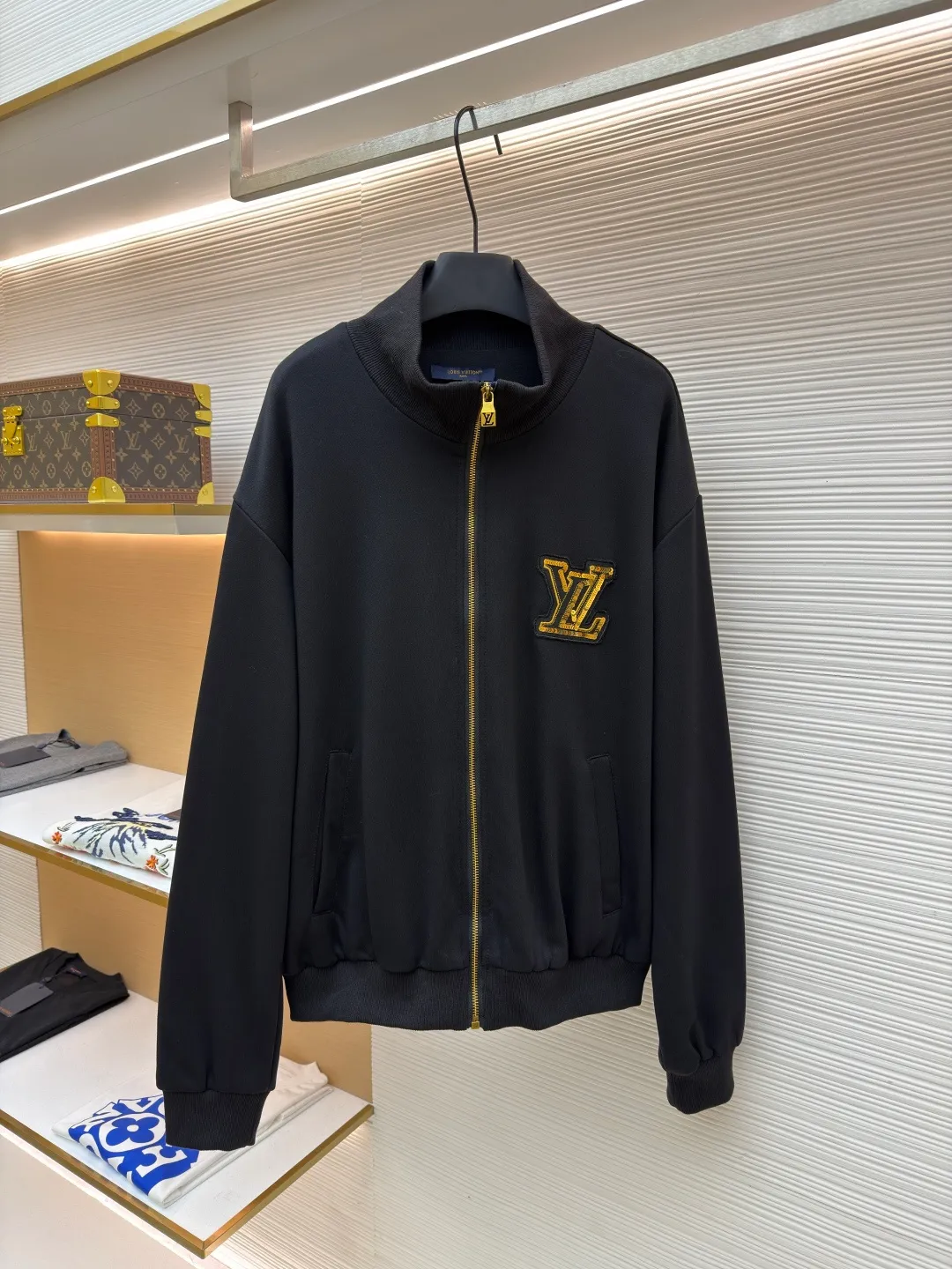 LOUIS VUITTON stand-up collar ribbed hem long-sleeved logo decorated jacket ●Original version: Purchased and developed at 25899 ●Item number: 1682404-B25 ●Fabric: cotton fabric ●Technology: knitted production ●Color: black ●Version: fitted version ●Weight: about 990 grams ●Size: S-M-L-XL ●Description: This Louis Vuitton stand-collar zipper jacket is made of high-thread-count cotton-elastic blended fabric, which has been treated with enzyme washing process. The fabric is soft to the touch and has good wrinkle resistance and elasticity. The body has a delicate matte texture. The LV logo on the chest uses a combination of gold thread embroidery and patchwork. The embroidery uses interlaced flat stitch and chain stitch techniques. The stitch density reaches 12 stitches per centimeter. The edges are overlocked and the pattern is three-dimensional and not easy to fall off. The jacket adopts a stand-up collar design, and the collar ribs are made of spandex blended material, which has been shaped to ensure that it will not loosen after long-term wear. The front is equipped with a custom brass zipper, and the zipper teeth are polished and gold-plated, making it smooth, wear-resistant and of high-quality texture. The side seam pockets are welted, and the seams are reinforced with double-needle sewing. The ribbed edges of the cuffs and hem are woven with high-elastic yarns of the same color. The shoulders are seamlessly spliced ​​with natural shoulder shapes. The overall craftsmanship combines the brand's classic elements with practical design, fully demonstrating the production level of high-end clothing. The overall wiring is straight and delicate, the fabric is comfortable and soft, and the color is consistent without color difference. It can be matched with the same style to create a fashionable look and control various occasions. Customized accessories, complete with three standards, same style for men and women!